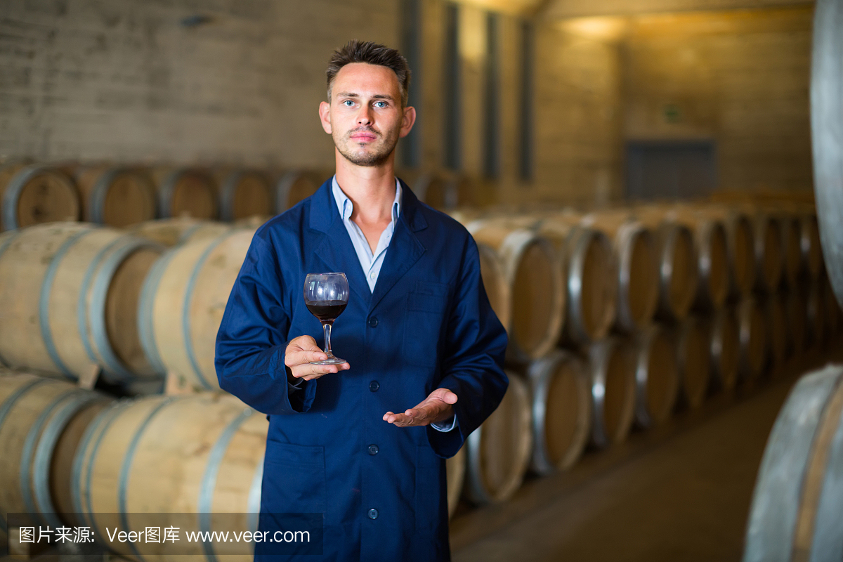 酒莊員工拿著裝在玻璃杯里的葡萄酒樣品